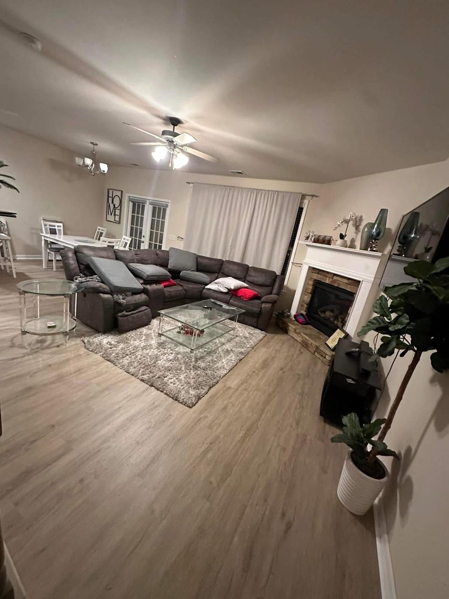 A living room a family has moved back into. Wide plank in a warm grey oak, running the length of the open plan.