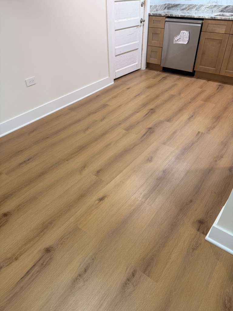 Warm oak plank laid tight to the baseboard and cut around the dishwasher and cabinet run.